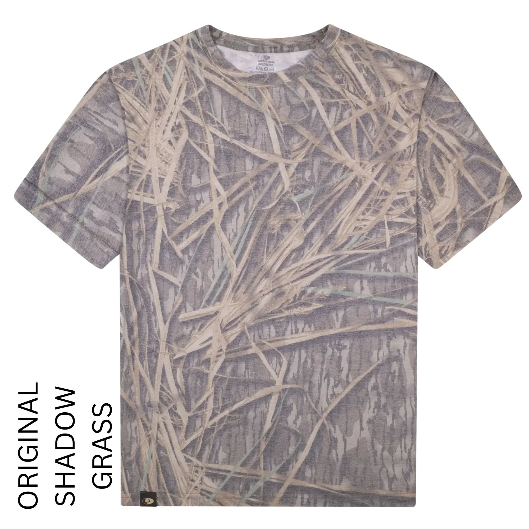 A short-sleeve crewneck t-shirt featuring an all-over 'Original Shadow Grass' camouflage pattern with realistic reeds and branches in shades of gray, beige, and brown, shown against a plain white background with text overlay on the left.